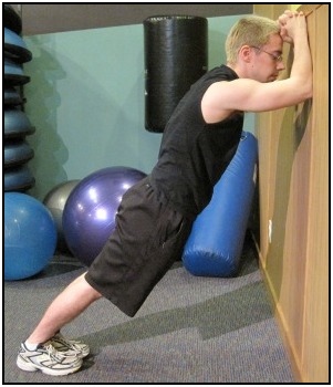 Standing calf stretch against the wall, with both feet back.